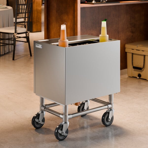 A stainless steel portable ice bin with bottle holders and a sliding lid on wheels.