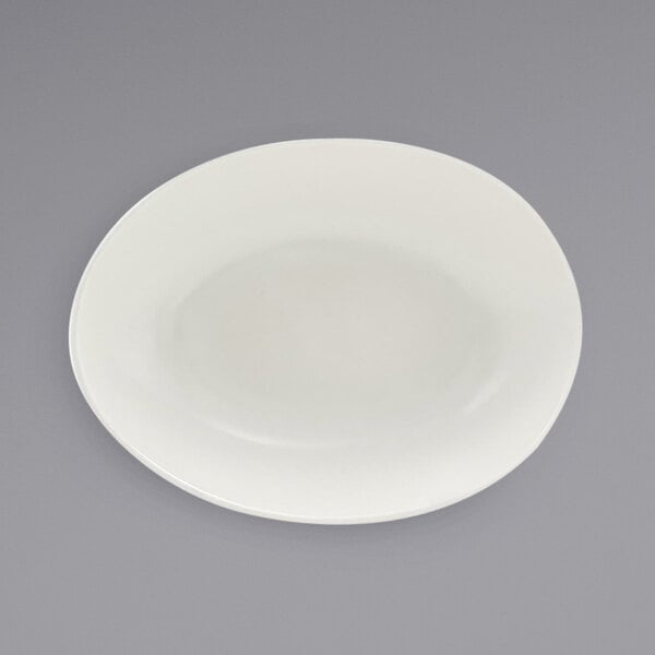 A white semi-matte scallop oval porcelain bowl on a gray surface.