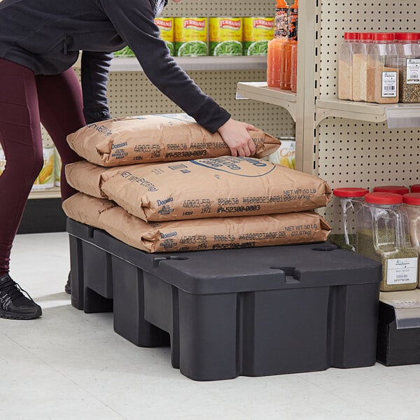 A black plastic Regency display base with brown bags stacked on top.