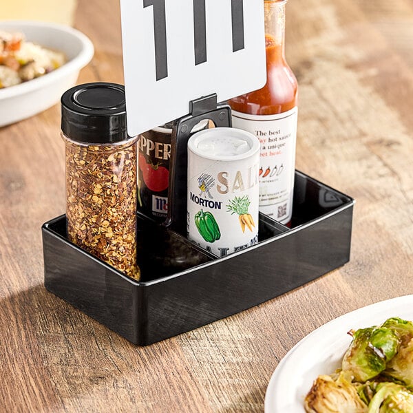 A black Carlisle condiment caddy with a white sign on it.