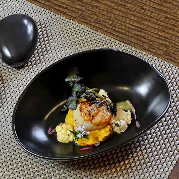 A black oval porcelain bowl filled with food.