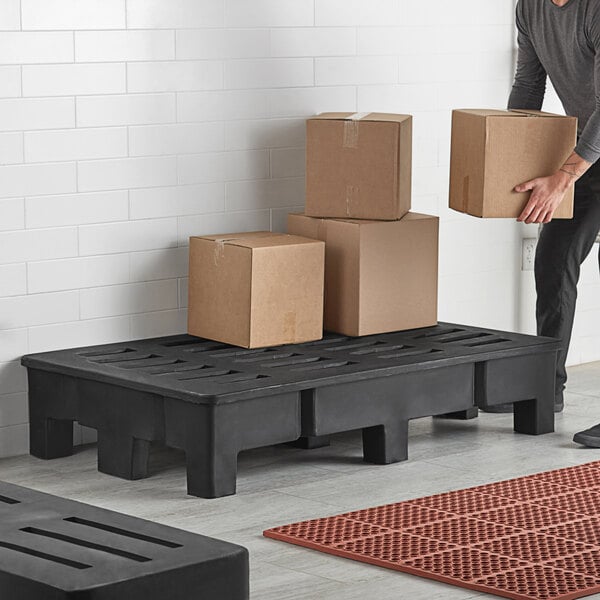 A man holding boxes on a black Regency dunnage rack with a slotted top.