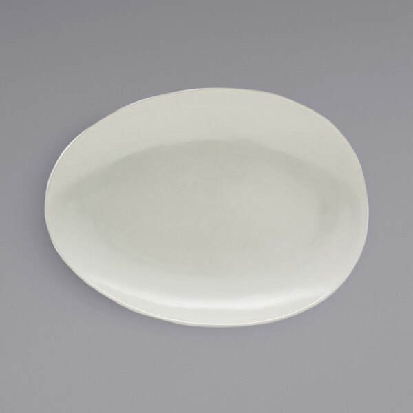 A white oval porcelain platter with a scallop design on the edge.