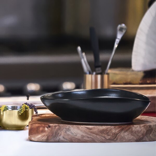 A close up of a black bowl on a wood surface.