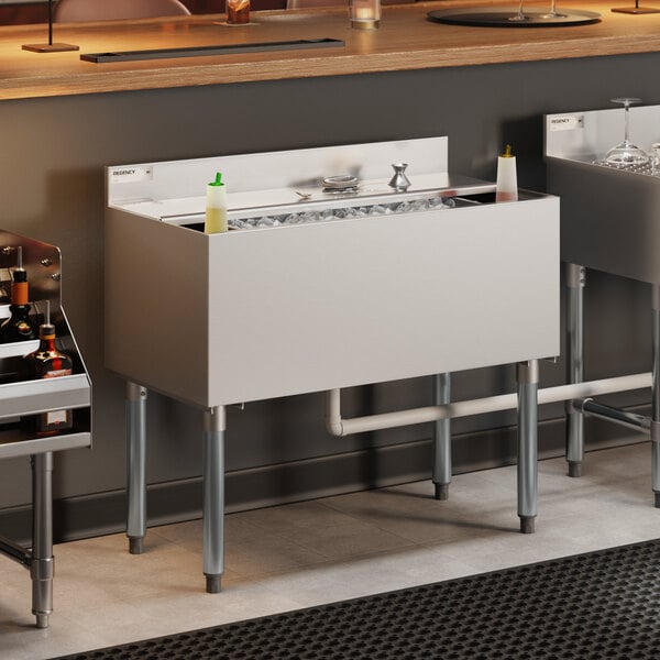 A stainless steel underbar ice bin with bottle holders and a sliding lid.