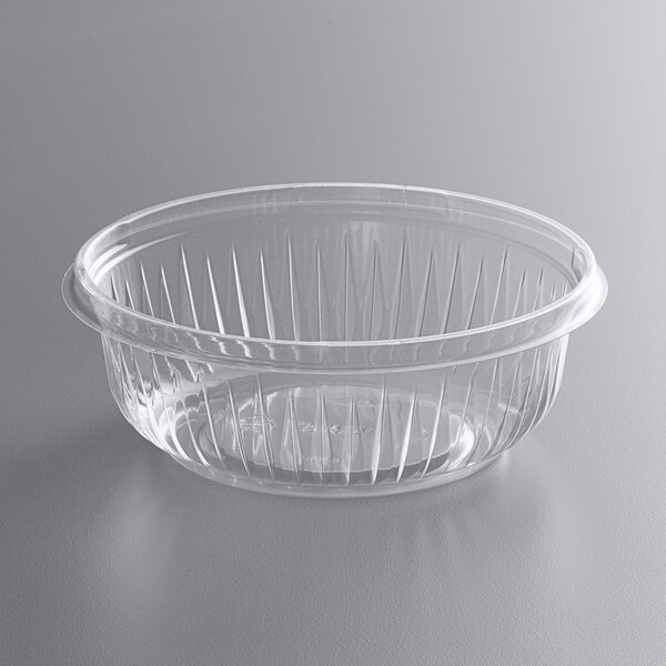 A Dart clear plastic bowl with a ribbed bottom on a gray surface.