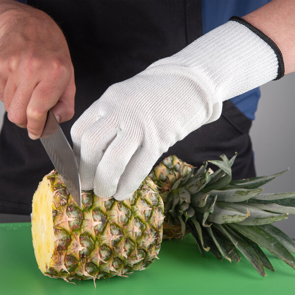 a person's hand with a knife cutting a pineapple