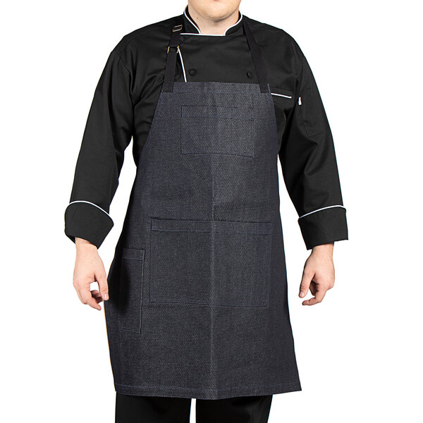 A man wearing a Uncommon Chef denim apron with black webbing.