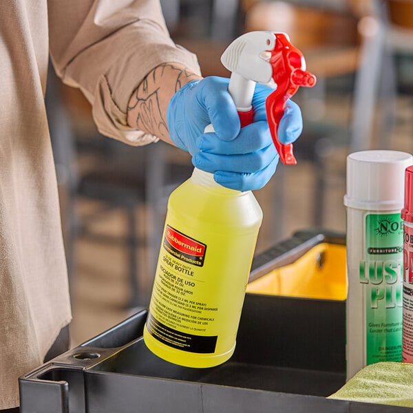 A person in blue gloves using a yellow Rubbermaid spray bottle.