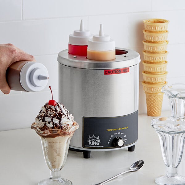 A person pouring a cherry topping onto a dessert in a glass using a Carnival King sauce bottle warmer.