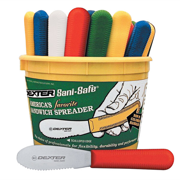 A white bucket filled with Dexter-Russell scalloped sandwich spreaders in assorted colors.