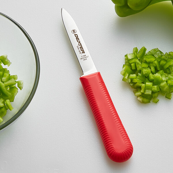 A Dexter-Russell Sani-Safe paring knife with a green handle next to chopped green peppers.