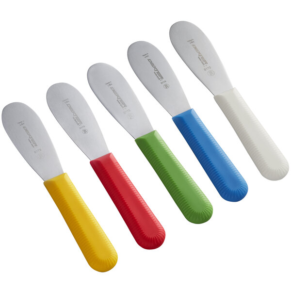 A close-up of a Dexter-Russell bucket of 48 assorted colored sandwich spreaders with smooth blades and yellow handles.