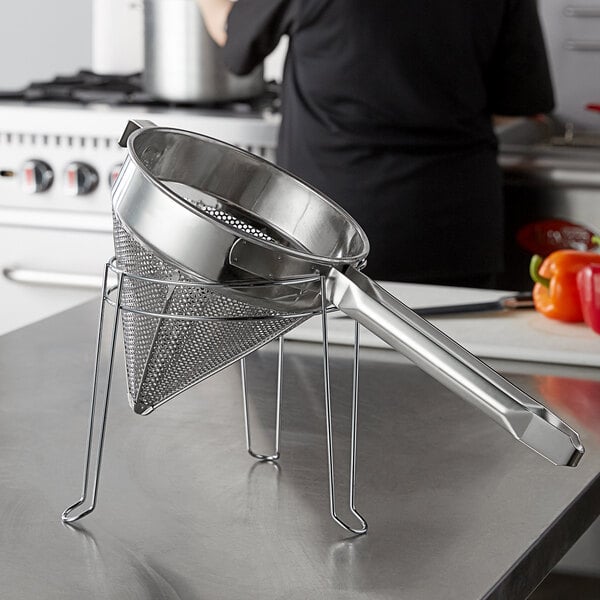 A Choice stainless steel strainer and stand set on a counter.