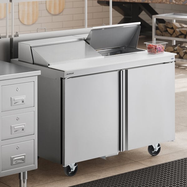 A stainless steel two-door refrigerated sandwich prep table with a raised ingredient rail and casters.