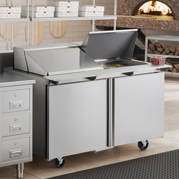 A stainless steel, two-door refrigerated sandwich prep table with a mega top and casters.