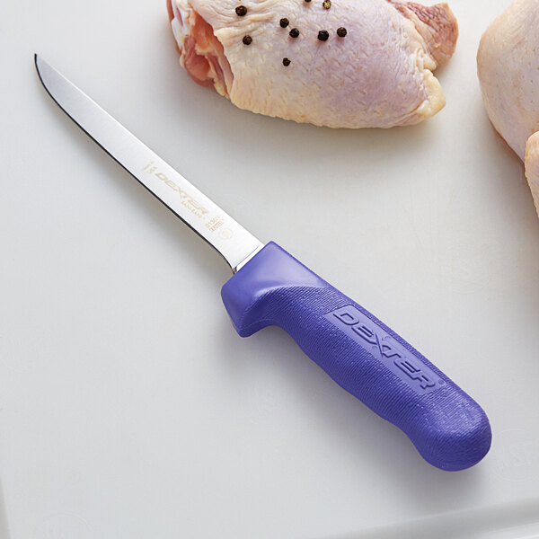 A Dexter-Russell purple narrow boning knife with a blue handle on a white surface next to a piece of chicken.