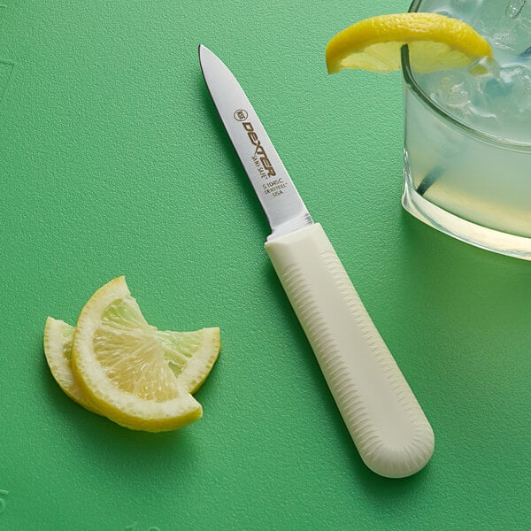 A Dexter-Russell Cook's Style Paring Knife next to lemon slices on a green table.