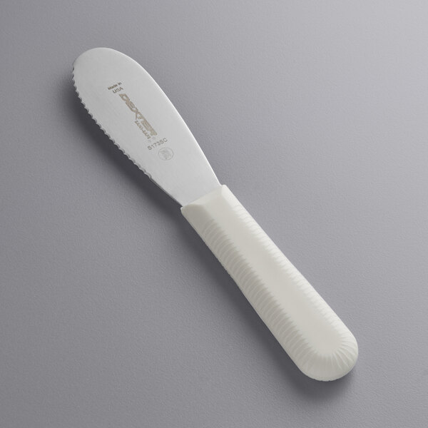 A Dexter-Russell Sani-Safe scalloped sandwich spreader with a white handle.