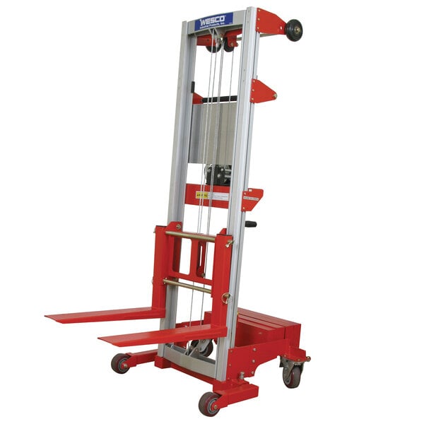 A red and silver Wesco counter-balance hand winch lift with white straddle base and forks.