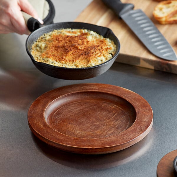 A hand holds a pan of food over a Valor rustic chestnut underliner.