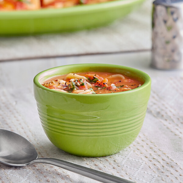 An Acopa Capri green bamboo bouillon bowl filled with soup with a spoon.