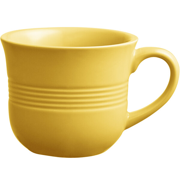 A close-up of a yellow Acopa Capri stoneware coffee cup with a handle.