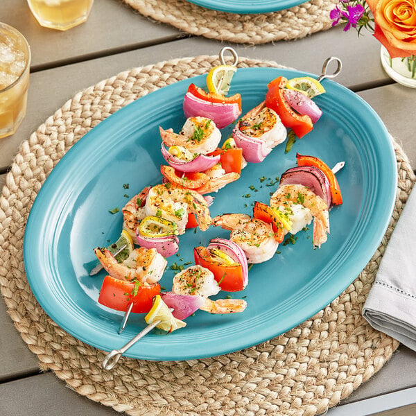 An Acopa Caribbean turquoise oval stoneware platter with food on it.