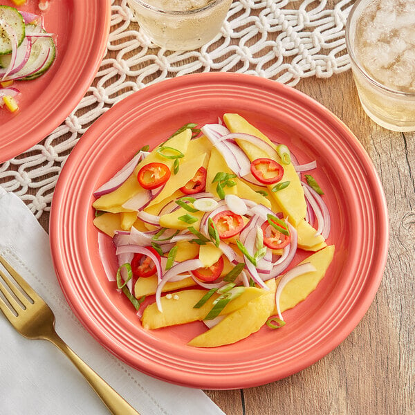 A Acopa Capri stoneware plate with mango salad, onions, and red peppers on a table.