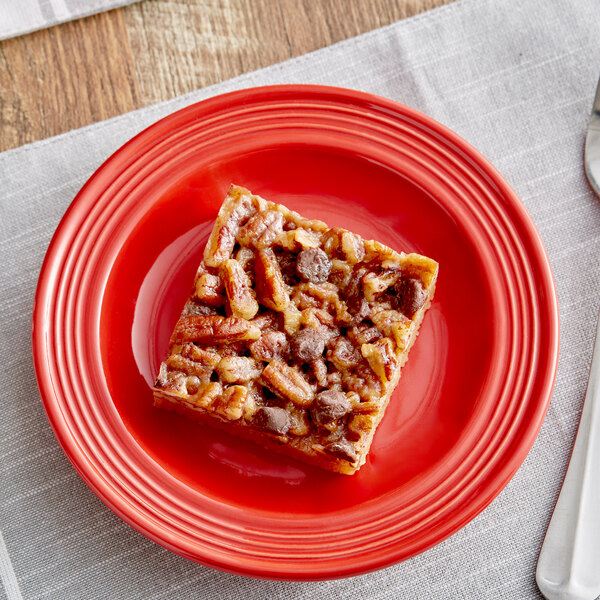 A square piece of bacon and cheese on a red Acopa Capri stoneware plate.