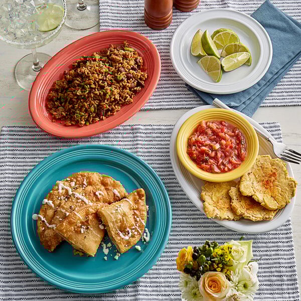 A table in a Mexican restaurant set with Acopa Capri Caribbean turquoise stoneware plates filled with rice, beans, and a bowl of salsa.