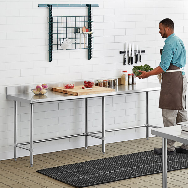 A man standing in front of a Regency stainless steel open base work table.