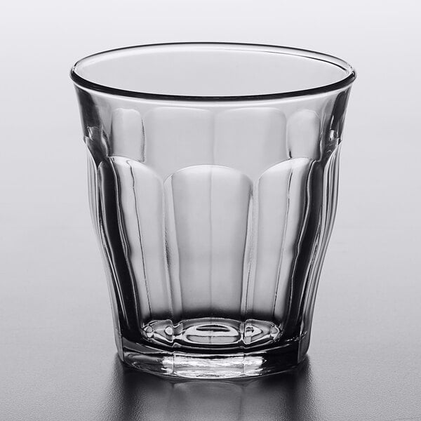 A Duralex Picardie clear glass tumbler on a white table.