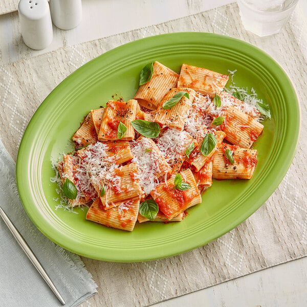 A Acopa Capri bamboo oval platter with pasta and basil on it.