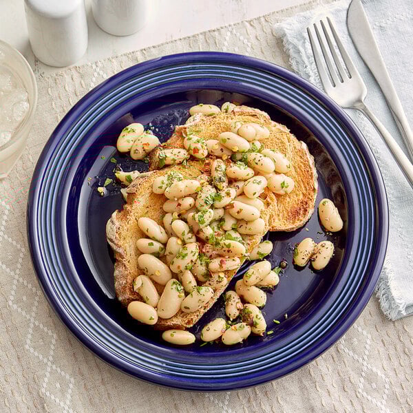 An Acopa Capri stoneware plate with a plate of food with beans and herbs on it.