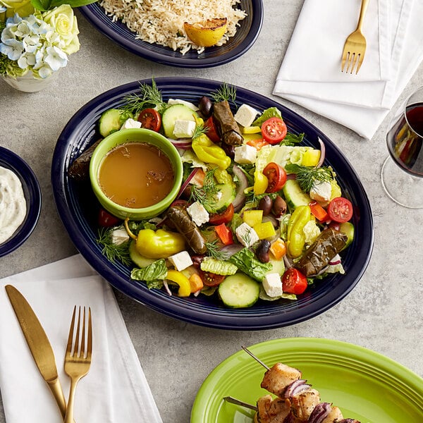 A table with a plate of rice, a green Acopa Capri stoneware bowl with a brown liquid, and a wedge of lemon.