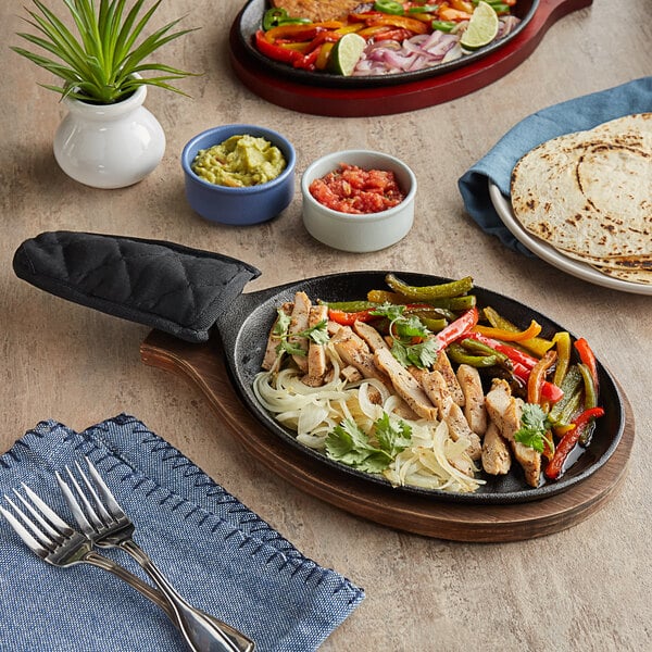 A Choice cast iron fajita skillet with food on a table.