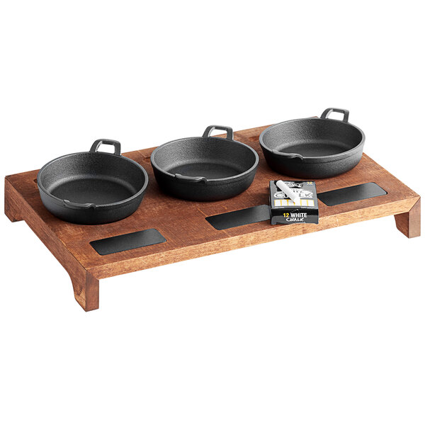 A group of black cast iron pans on a wooden display stand.