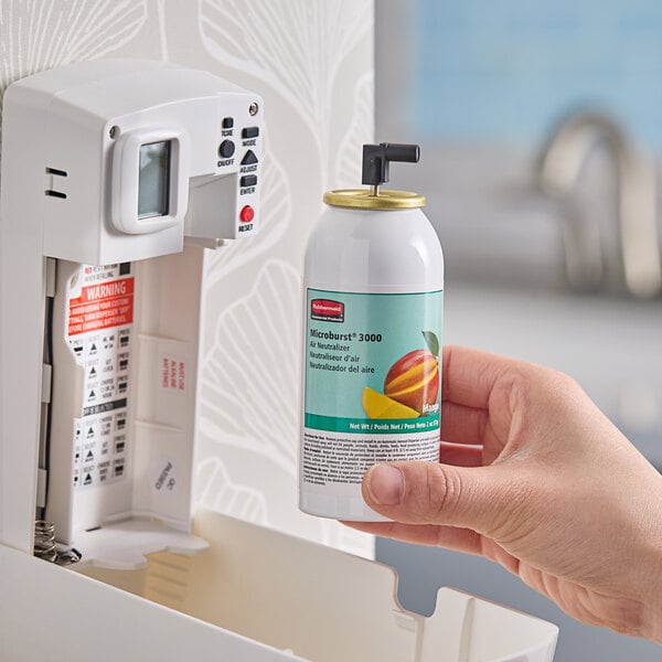 A hand holding a Rubbermaid Mango Metered Aerosol Air Freshener canister.
