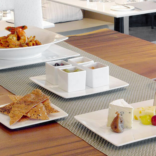 A white square porcelain plate with food on it on a table.