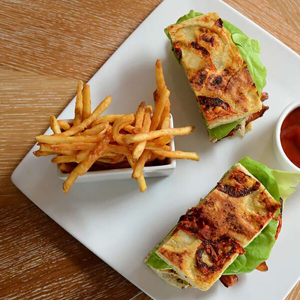 A sandwich and fries on a Front of the House white square porcelain plate.