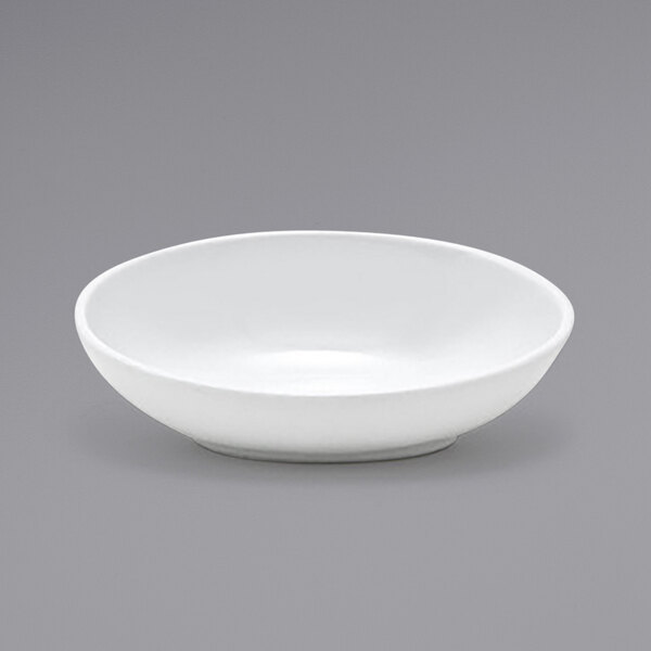 A Front of the House white oval ramekin on a gray surface.
