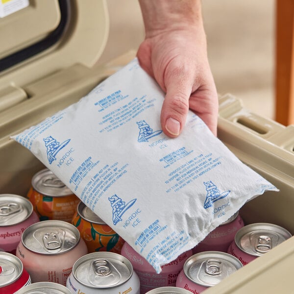 A Nordic NS24 24 oz. No Sweat Gel Cold Pack being placed into a cooler with canned beverages.