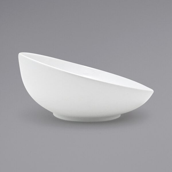A close-up of a white Front of the House Ellipse porcelain bowl with a curved edge.