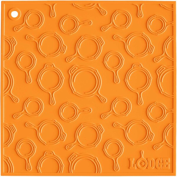 An orange square Lodge silicone trivet with a skillet pattern.
