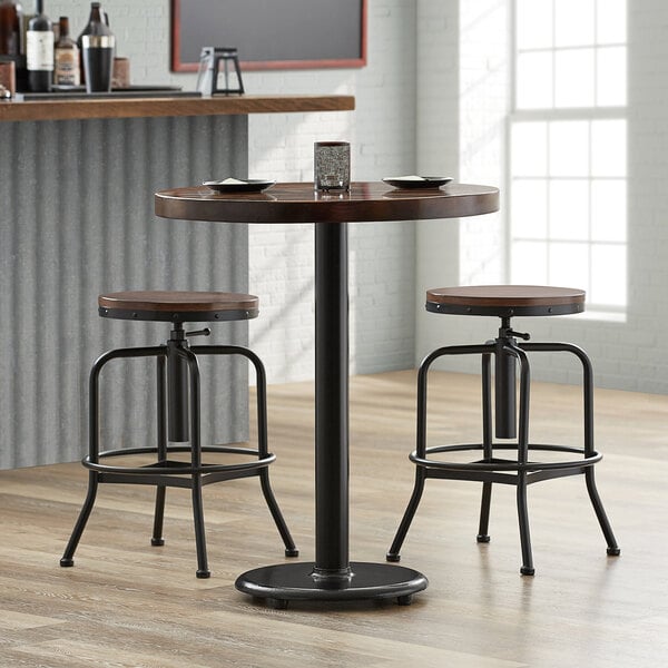 A Lancaster Table & Seating cast iron counter height table base with wooden stools.