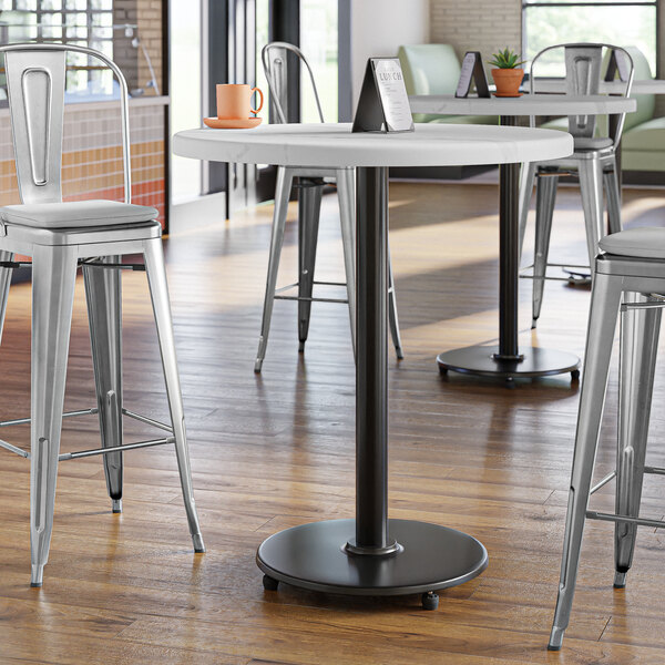 A white round table with a Lancaster Table & Seating cast iron bar height table base.