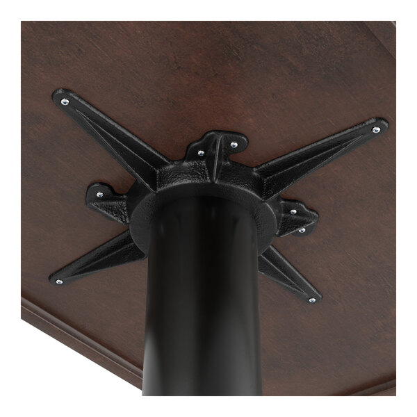 A Lancaster Table & Seating black cast iron table base with a black metal post on a table.