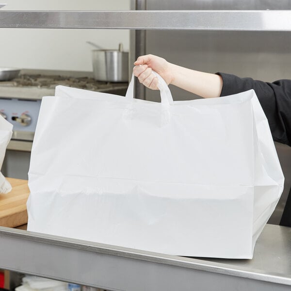 A woman in a black uniform holding an LK Packaging plastic take out bag.