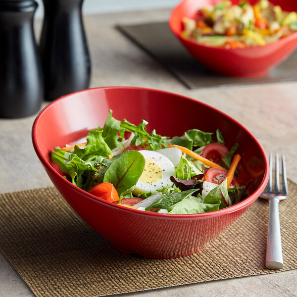 A GET crimson melamine bowl filled with salad with egg and tomatoes on a table.